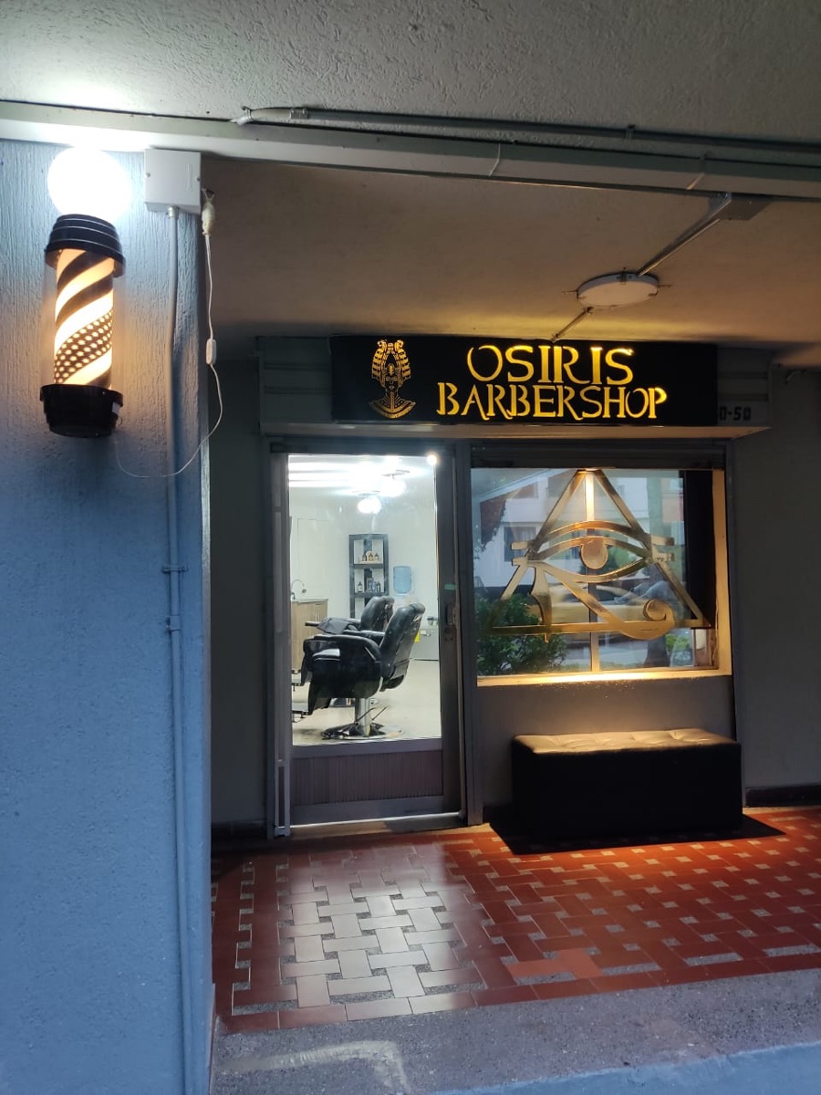Fachada de Barbershop Osiris de noche, en el Primer Parque de Laureles
