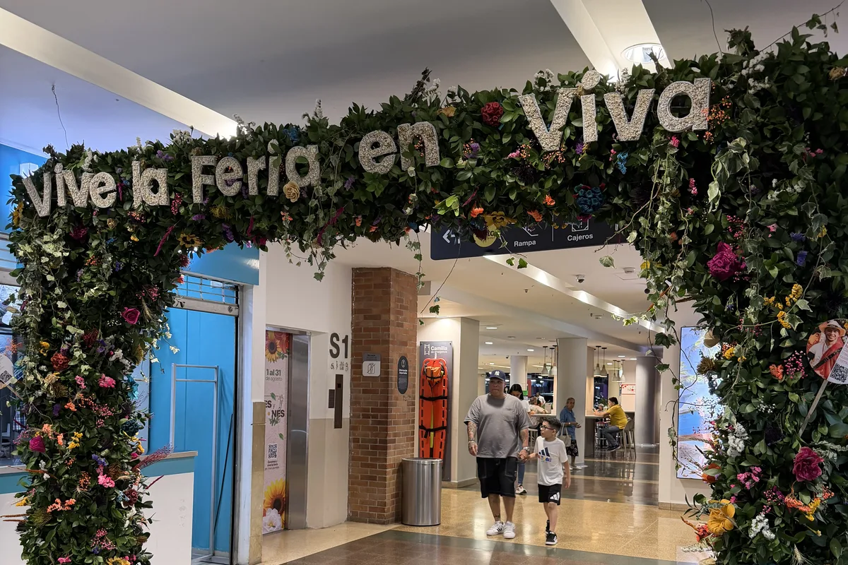 Flower arch reading 'Vive la Feria en Viva' inside Viva Laureles shopping centre